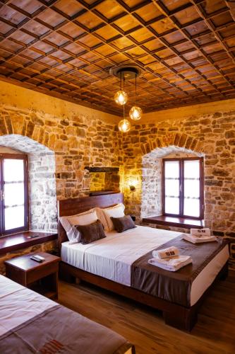 a bedroom with two beds and a stone wall at Vila Blin in Berat
