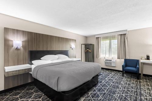 a hotel room with a large bed and a blue chair at Quality Inn Oskaloosa in Oskaloosa