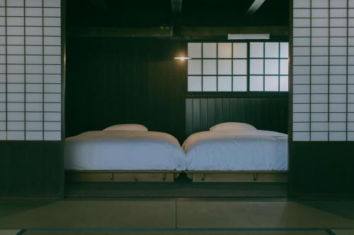 two beds in a room with two windows at 暇家 kaya in Yosano