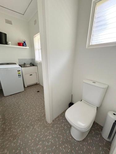 a bathroom with a white toilet and a window at Conns Cottage - Bring your own linen in South West Rocks