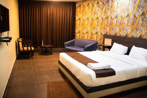 a bedroom with a large bed and a blue chair at Aira Suites in Bangalore