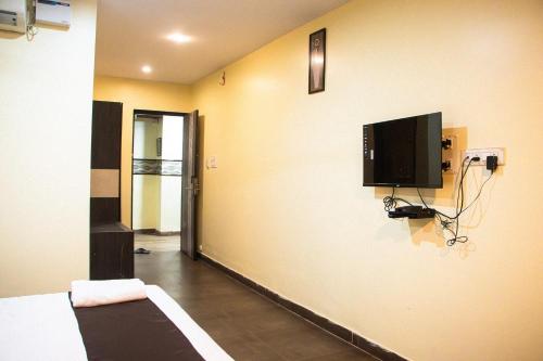 a room with a bed and a tv on the wall at Aira Suites in Bangalore
