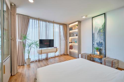 a bedroom with a bed and a flat screen tv at Cactusland Boutique Hotel in Ho Chi Minh City