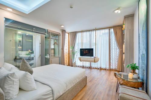 a bedroom with a large white bed and a television at Cactusland Boutique Hotel in Ho Chi Minh City
