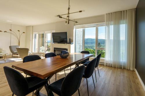 a dining room with a wooden table and chairs at 304 - Chic Minimalist Condo - River & Serenity in Baie-Saint-Paul