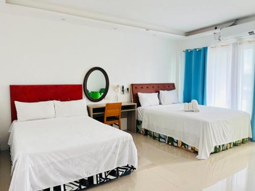 a bedroom with two beds and a desk and a mirror at Shiri Hotel in Silang