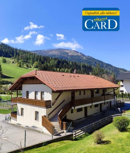a house with a red roof with a hill in the background at Appartements Bel Monte - Kärnten Card im Sommer inklusive in Bad Kleinkirchheim