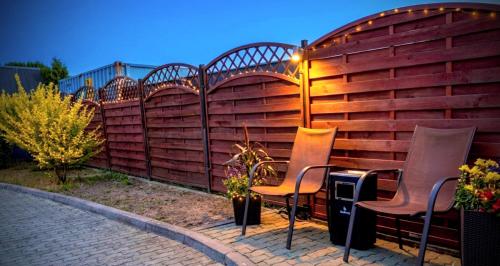 a fence with two chairs and a table with a light at Villa Aqua in Międzyzdroje