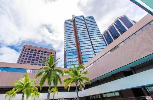 two palm trees in front of a tall building at Executive Center Hotel Honolulu in Honolulu