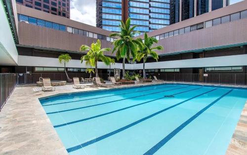 a large swimming pool with palm trees in front of a building at Executive Center Hotel Honolulu in Honolulu