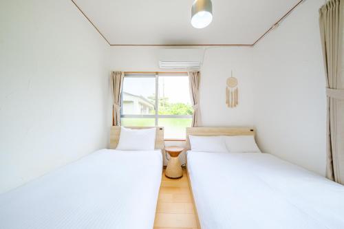 two beds in a room with a window at ふんわり in Miyakojima