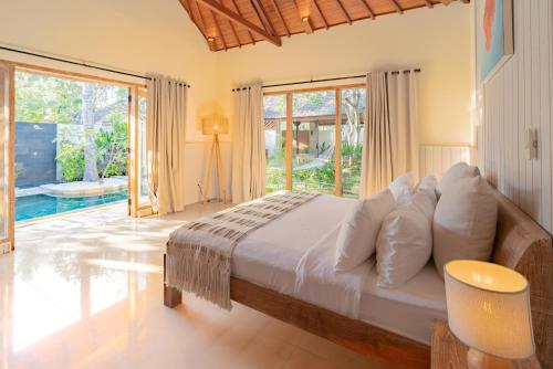 a bedroom with a bed and a large window at Kelapa Villas in Gili Trawangan