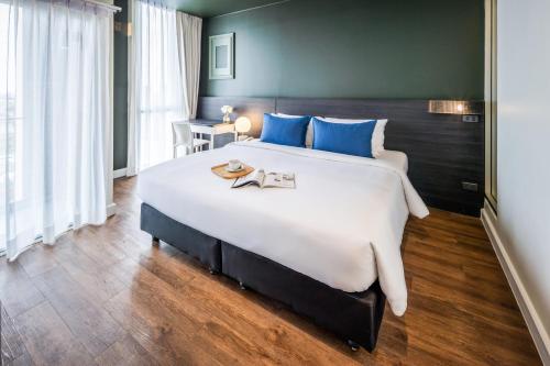 a bedroom with a large bed with blue pillows at Blue Hippo & Red Crocodile Hotel in Bangna