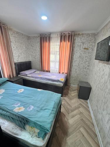 a room with two beds and a television in it at Sharshara-Darvoz in Sangovy