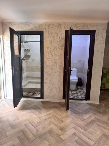 a bathroom with a toilet and two glass doors at Sharshara-Darvoz in Sangovy