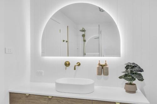 a white bathroom with a sink and a mirror at Callow Place 10 in Bermagui