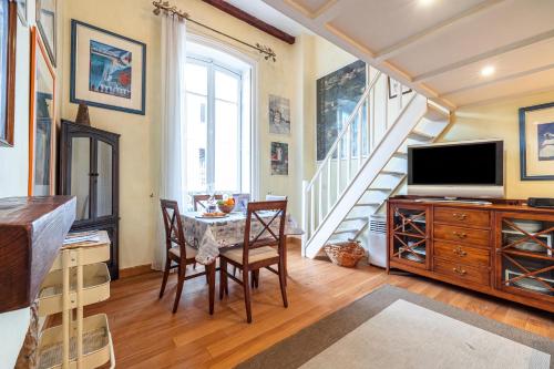 a dining room with a television and a table with chairs at Regina - Duplex in Heart of Menton - Happy Rentals in Menton