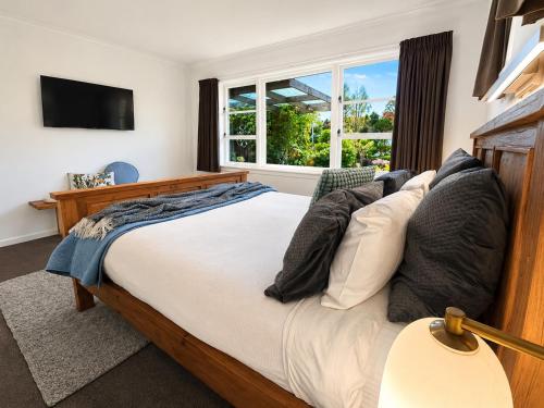 a bedroom with a bed with pillows and a window at Redwoods Retreat Rotorua Private 3BR Home in Rotorua