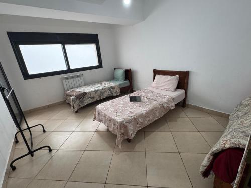 a room with two beds and a table and a window at Residence Jade in Bir el Djir