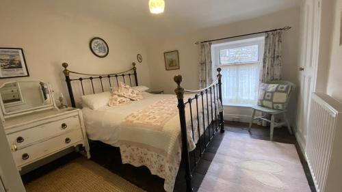 a bedroom with a bed and a dresser and a window at Sunnyside Cottage in Sedbergh