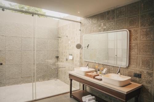 a bathroom with two sinks and a shower with a mirror at Arth Resorts I Convention I Wellness in Moinabad