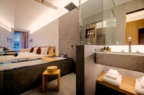 a bathroom with a tub and a sink and a bed at Muni Kyoto in Kyoto