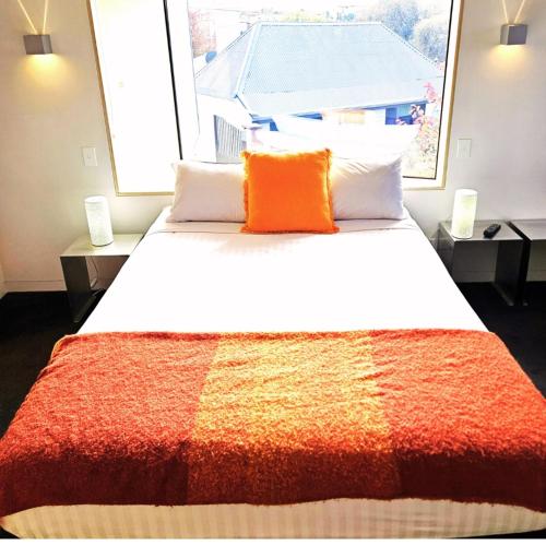 a bedroom with a large bed with an orange pillow at Fusion Townhouse-North Hobart in West Hobart