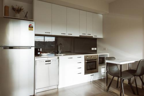 a kitchen with white appliances and a table and chairs at Montage Apartment + Views + Location + Car Parking in Bellerive