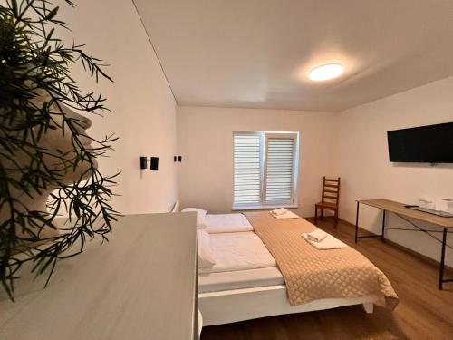 a bedroom with a bed and a desk and a television at Pakalnės sodyba in Skverbai