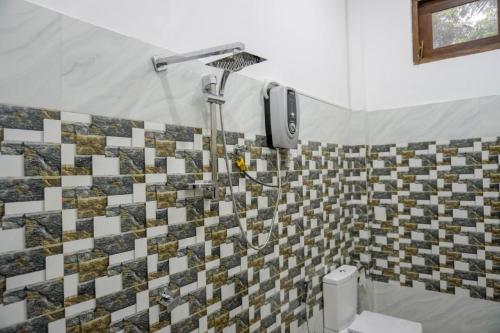 a shower in a bathroom with a tiled wall at Lake View Eco Lodge in Dambulla