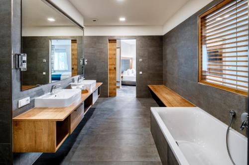 a bathroom with three sinks and a bath tub at Hotel Schwan & Post in Bad Neustadt an der Saale