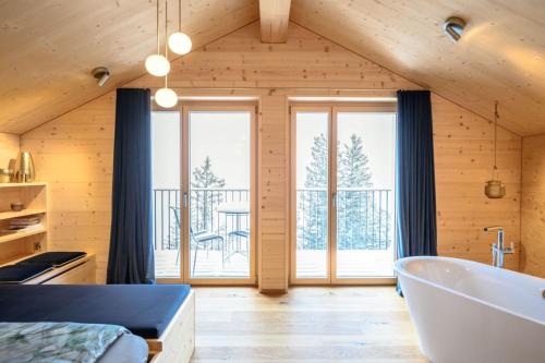 a room with a tub and a bedroom with a balcony at Berglodge37 in Altdorf