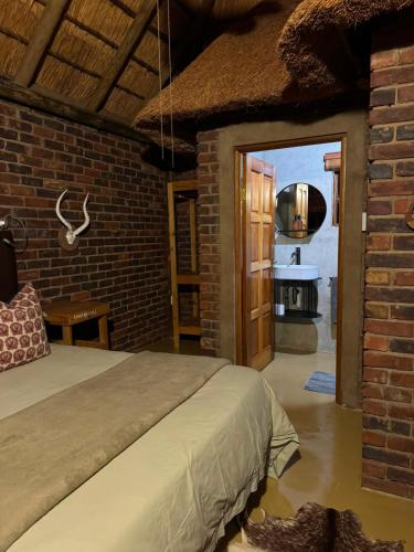 a bedroom with a bed and a brick wall at Vilagama Game Lodge in Naboomspruit