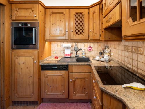 a kitchen with wooden cabinets and a sink at Villa Marmarole - Croda Bianca Apartment in Calalzo
