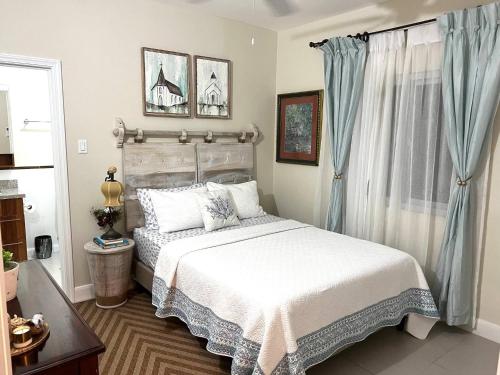 a bedroom with a white bed and blue curtains at Oceanpointe Serenity Get Away-solar pool WiFi in Lucea