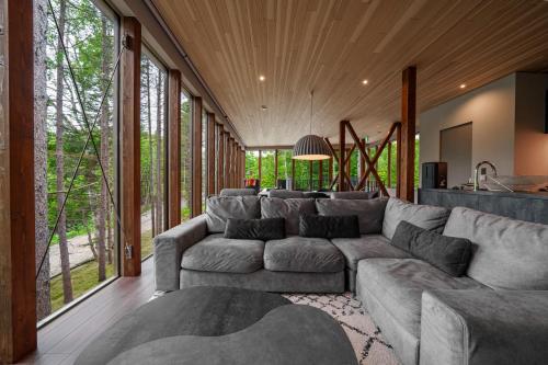 ein Wohnzimmer mit einem großen Sofa und großen Fenstern in der Unterkunft Noah Rusutsu in Rusutsu