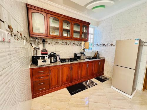 a kitchen with wooden cabinets and a refrigerator at Stargate Apartments in Arusha