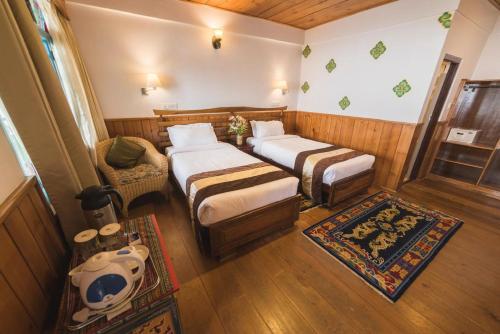 a room with two beds and a couch and a chair at Netuk House a heritage boutique stay in Gangtok