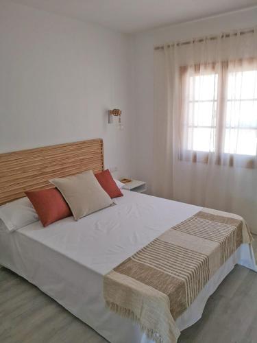 a bedroom with a large white bed with red pillows at Nice apartment with a pool in Fornells
