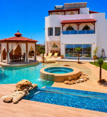 a house with a swimming pool in front of a house at Luxury Beachfront Villa with Pool and Jacuzzi in Hennchir Ksar Rhaleb