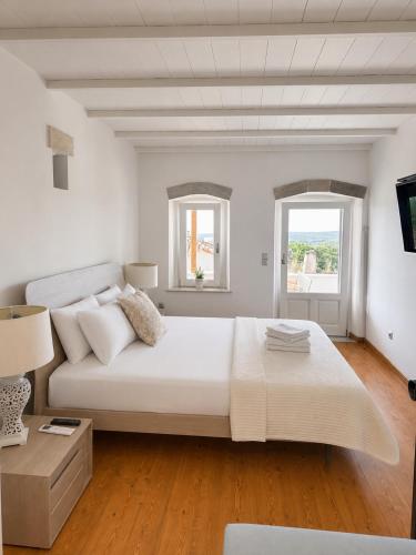 a white bedroom with a large bed and two windows at Kytheros in Potamós
