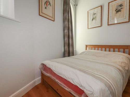 a bed in a bedroom with two pictures on the wall at Farthings, The Old Chapel in St Austell