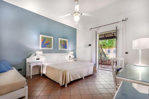 a bedroom with a bed and a table and a window at iGV Club Baia Samuele in Sampieri