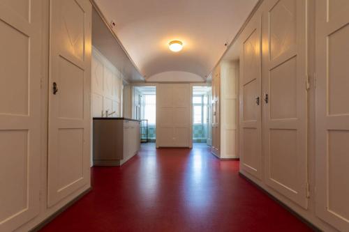 an empty hallway with white doors and a red floor at Centrally Located Room in Buchs