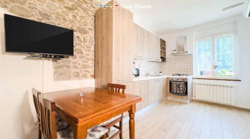 a kitchen with a wooden table and a tv on the wall at Il Volto, Terre Marine in Pignone