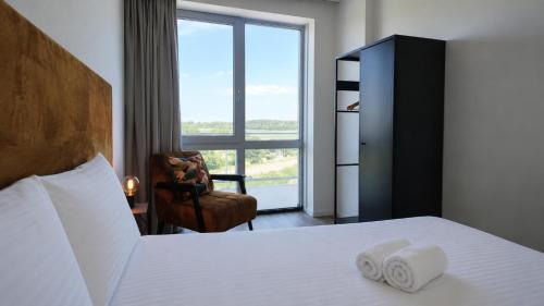a bedroom with a bed and a chair and a window at Residentie De Zeester | De Schelp in Scherpenisse