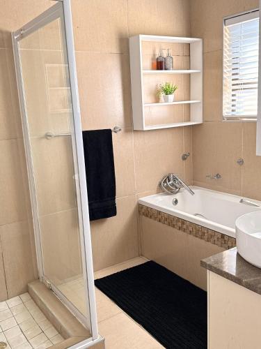 a bathroom with a shower and a tub and a sink at High tide complex in Langstrand