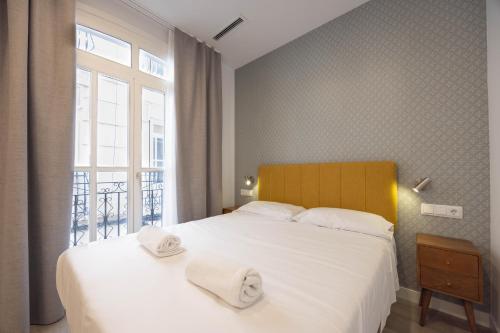 a bedroom with a large white bed with towels on it at Apartamento Nova by Cartagena Spain in Cartagena