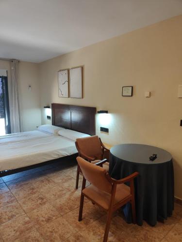 a bedroom with a bed and a table and chairs at Hotel La Jara-Arribes in Aldeadávila de la Ribera