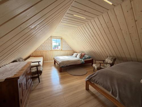 a attic room with two beds and a window at Koronkowa Chatka w Beskidach in Istebna